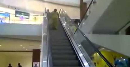 (VIDEO) Žena snimljena u pokušaju da se popne pokretnim stepenicama na drugi sprat ali nikako da shvati da stepenice ne idu u 'njenom pravcu'!