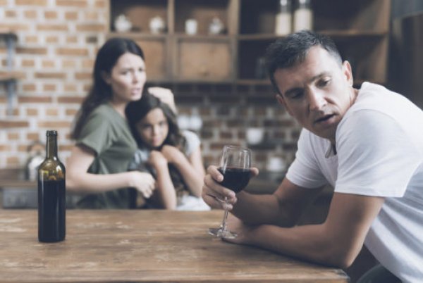man-drinking-wine-with-sad-family-in-background-522x350