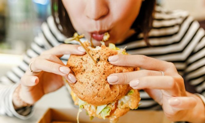 young-woman-eating-fast-food-chicken-sandwich-768